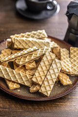 Sweet crispy wafers on plate on wooden table.