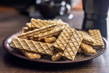 Sweet crispy wafers on plate on wooden table.