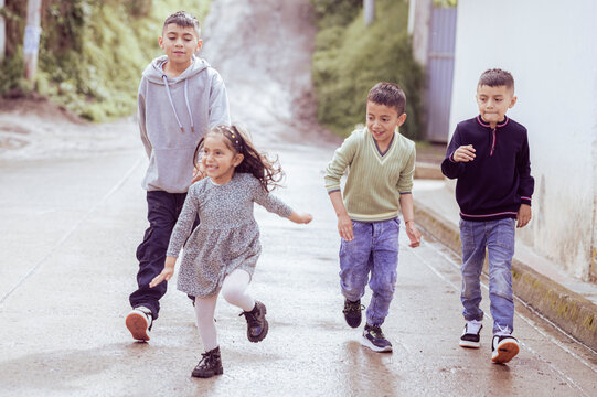 Four latin american children running down the street