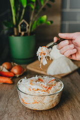 Man holding fork with fresh sauerkraut on the table