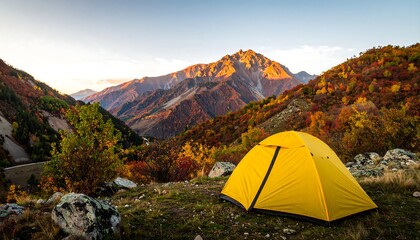 A vibrant autumnal landscape showcases a bright yellow tent nestled amidst a valley of colorful trees and rugged mountains.
