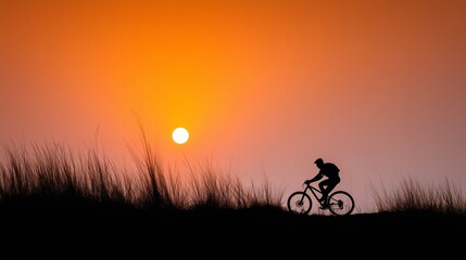 Obraz premium Man riding bicycle in silhouette at sunset. Cyclist on a bike with golden sun in orange sky. Concept of freedom and sport.