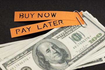 BNPL or Buy Now Pay Later concept. Dollar bills and label with message on black background