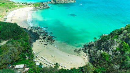Vista aérea da Praia do Cachorro em Noronha revela mar transparente, areia clara e falésias...