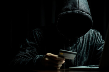 Individual in dark hoodie engaging in suspicious online activity at night