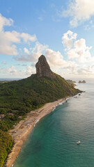 Naklejka premium Vista aérea do Morro do Pico em Fernando de Noronha, cercado por mar azul-turquesa e vegetação tropical, formando uma das paisagens mais impressionantes e fotografadas do litoral brasileiro