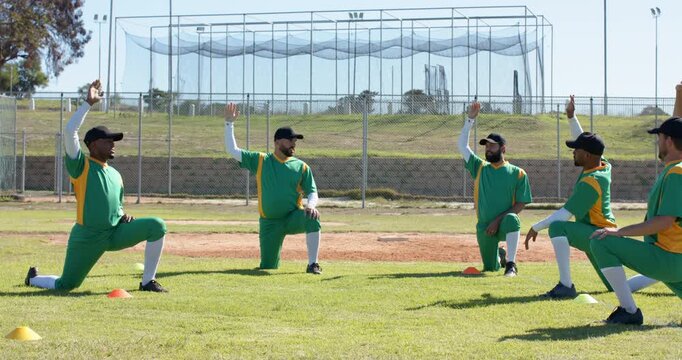 Count signaling male cricket teammates kneeling by marker cones on pitch stretching and warming up - Powered by Adobe