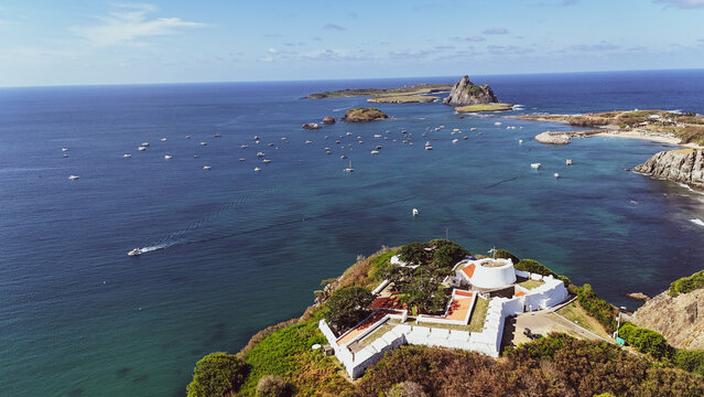 Vista a&eacute;rea do Forte de Fernando de Noronha, com suas muralhas hist&oacute;ricas contrastando com o mar azul e a paisagem tropical da ilha paradis&iacute;aca