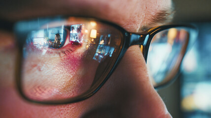 Close-up of glasses with screens reflected in the lenses &mdash; concentration, data work and digital analytics seen in the reflection.