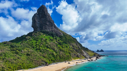Vista a&eacute;rea do Morro do Pico em Fernando de Noronha, destacando seu formato ic&ocirc;nico, vegeta&ccedil;&atilde;o nativa e a costa azul ao fundo, cen&aacute;rio perfeito para fotografia, turismo e contempla&ccedil;&atilde;o de paisagens 