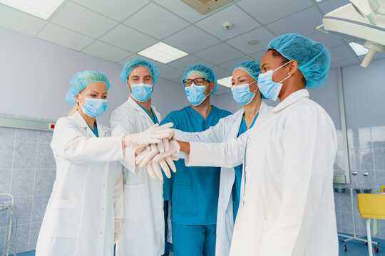 Team of Diverse Doctors in Scrubs and Masks Collaborating in a Bright Hospital Environment