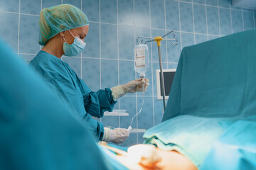 Healthcare Worker In Surgical Scrubs Monitoring Medical Equipment During Operation In Modern Hospital Setting