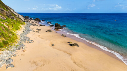 Praia da Conceição com águas claras, areia fina e costa rochosa, cenário icônico de Noronha.