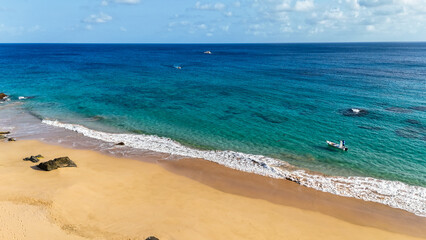 Orla de praia com águas claras e dia ensolarado, areia clara e clima tropical perfeito para...