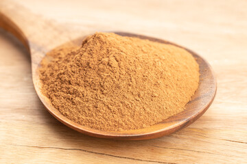 Cinnamon powder in wooden spoon on wooden table