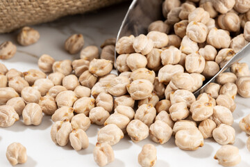 Close up of Chickpeas on scoop on White marble Background. Cicer arietinum