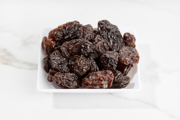 Close up of Raisins on plate isolated on White marble Background. Dried grape