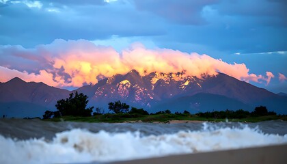 Colorful mountain range at sunset over a shoreline.