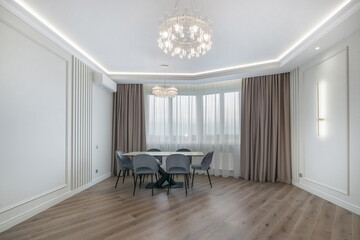 A stylish neoclassical dining area with elegant chandeliers and natural light coming 
through large windows.
