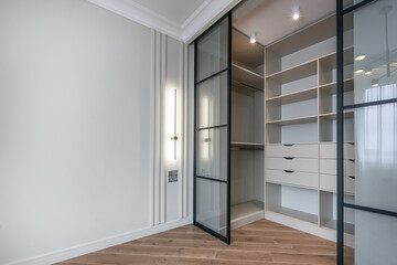 A modern dressing room with sliding glass doors combines functionality and aesthetics.