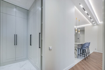 Modern interior design with grey built-in wardrobes, a chic kitchen with marble countertops and elegant bar stools in a modern apartment.