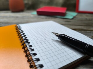 Close-up of fountain pen lying on blank notepad