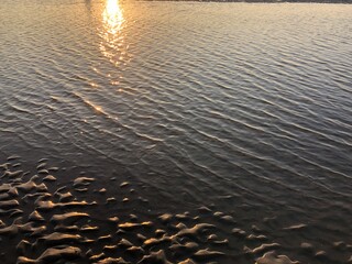 sunset gray beach wavy sand ripples water ocean or sea dune texture wallpaper pattern background close-up	