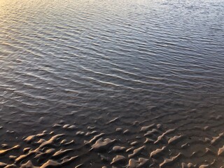 gray beach wavy sand ripples water ocean or sea dune texture wallpaper pattern background close-up	