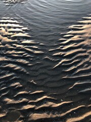 gray beach wavy sand ripples water ocean or sea dune texture wallpaper pattern background close-up	