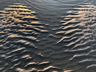 gray beach wavy sand ripples water ocean or sea dune texture wallpaper pattern background close-up	