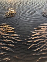 gray beach wavy sand ripples water ocean or sea dune texture wallpaper pattern background close-up	