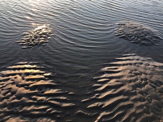 gray beach wavy sand ripples water ocean or sea dune texture wallpaper pattern background close-up	