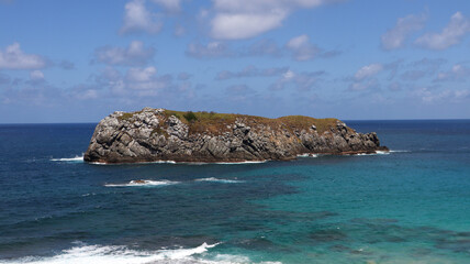 Formação rochosa isolada cercada pelo mar azul de Fernando de Noronha, destacando o contraste...