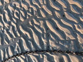 Textured beach sand with a metal chain tidal ripples texture background