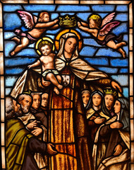 Fototapeta premium Stained glass window depicting religious figures and angels in a traditional church setting.