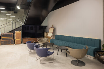 Modern office lobby with minimalist furniture, featuring black leather chairs, a round glass coffee table and piano