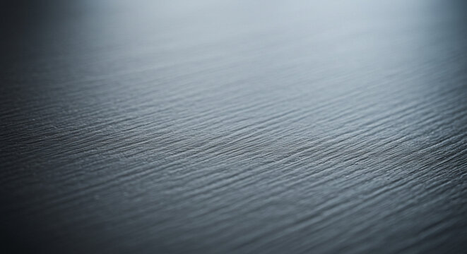 Closeup view of a dark, textured surface with parallel lines and subtle grain, creating an abstract background