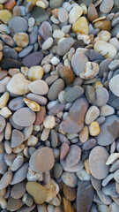 A close-up view of various smooth pebbles in different colors and sizes. The stones are rounded and polished, creating a natural texture.