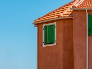 Mediterranean House with Green Shutters and Terracotta Roof under Blue Sky