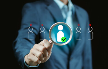 Businessman holding a magnifying glass selects a highlighted person icon among others, symbolizing recruitment, candidate selection, target marketing, and strategic partnership decision making.