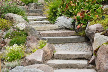 A set of stone stairs ascends next to a retaining wall made of large rocks in a public park in...