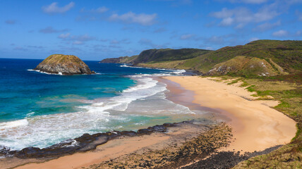 Praia do Leão em Fernando de Noronha, com areia dourada e mar cristalino, destacando o cenário natural e a tranquilidade do arquipélago.