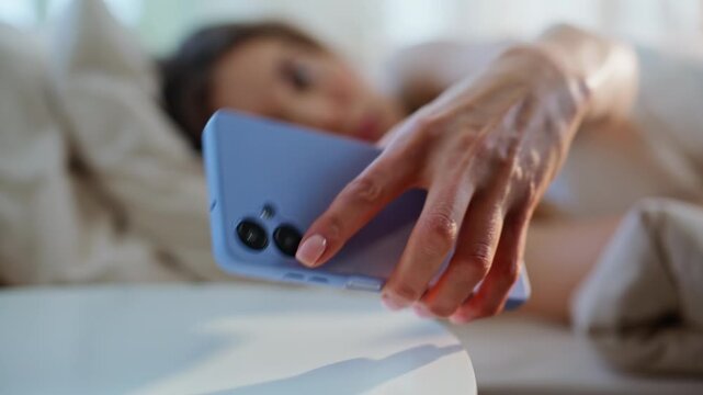Sleeping woman reaching phone wakeup in apartment closeup. Brunette taking 