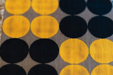 Close up of a pattern with alternating rows of yellow and black circles on a textured background