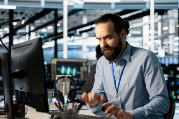 Server hub worker concerned after infrastructure failure errors found during analysis. Annoyed software developer in data center frowning at PC monitor after detecting unexpected network outage
