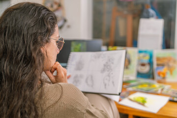 Graphic designer reviewing sketches in home studio
