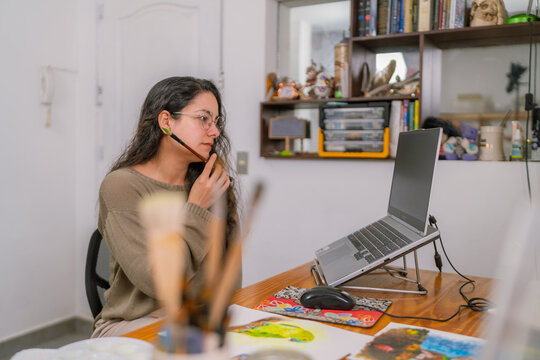 Graphic designer working from home studio using laptop and headset