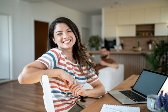 Happy woman working from home while man reading on sofa - Powered by Adobe