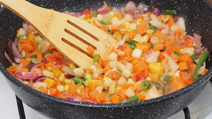 A woman fries vegetables in a frying pan at home. healthy food, diet, low calories, diet. cauliflower, green beans, peas, peppers, tomatoes. Vegetable saute in frying pan