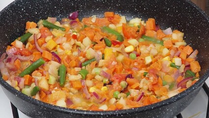 A woman fries vegetables in a frying pan at home. healthy food, diet, low calories, diet. cauliflower, green beans, peas, peppers, tomatoes. Vegetable saute in frying pan